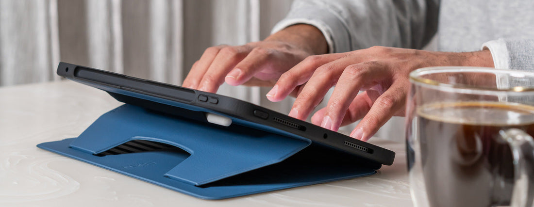 iPad in a blue ZUGU case propped up at a steep angle for typing, on a table with a coffee 
