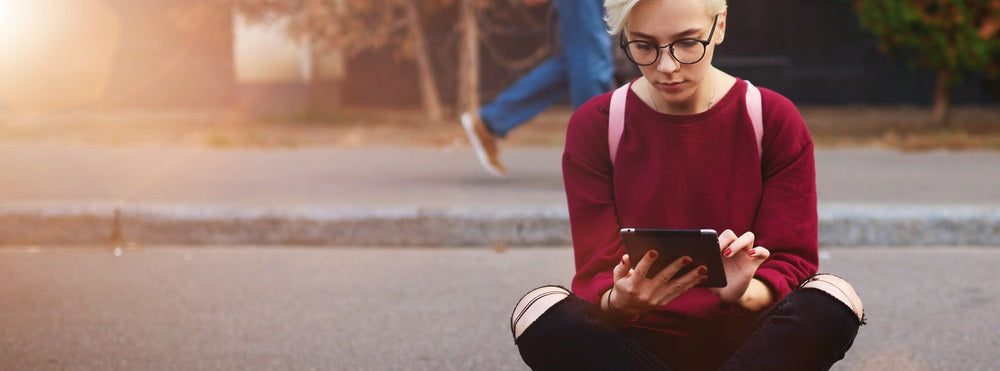 Person sitting on skateboard looking at iPad