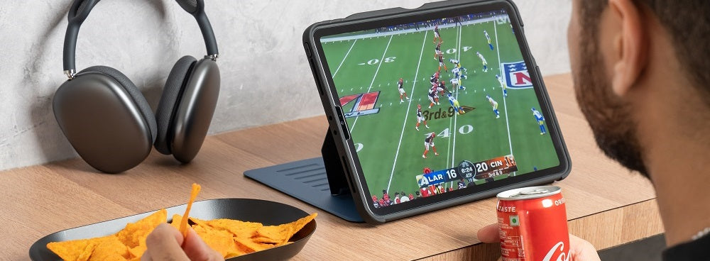Person watching an American football game on a tablet in a protective case