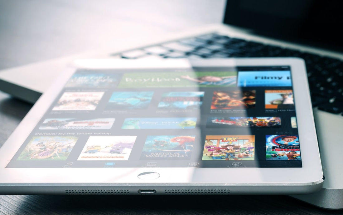 An iPad with a home button sits on a Macbook keyboard