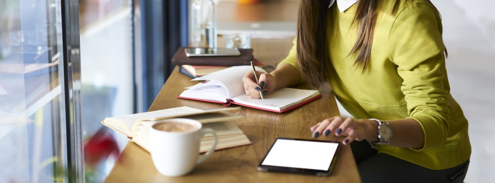 Women at bar looking at iPad and writing in notebook
