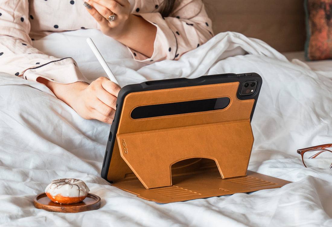 Someone sitting up in bed, using an iPad and Apple Pencil, with the iPad housed in a ZUGU case